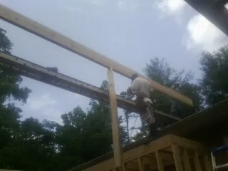 Carpenter setting a ridge beam over a new addition frame — Ice Dam Removal by Roofing Brothers in Turner