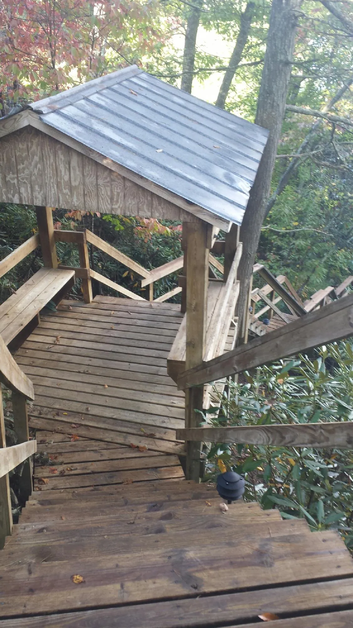 Metal roofed shelter over wooden steps on a wooded walkway — Skylight Repair & Installation work by our crew in Turner