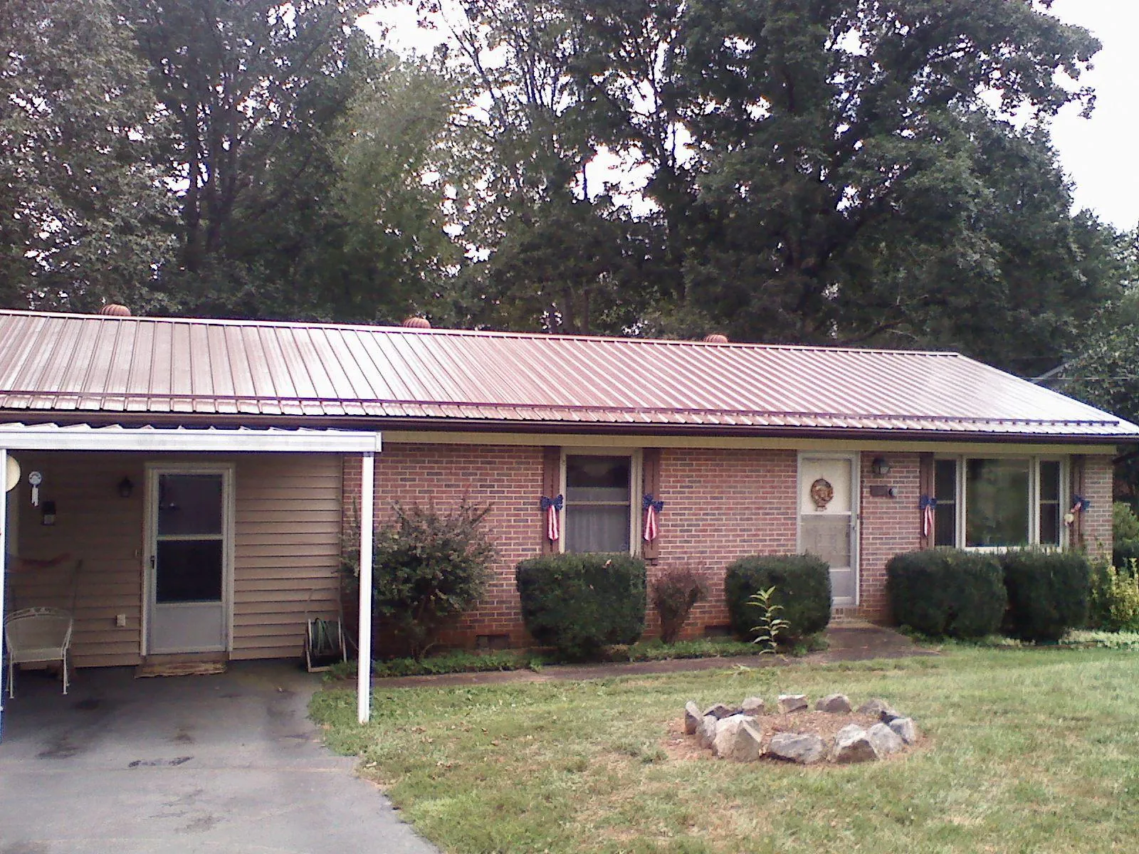 Bronze metal roof and carport on a brick ranch home — Roof Repair work by our crew in Turner