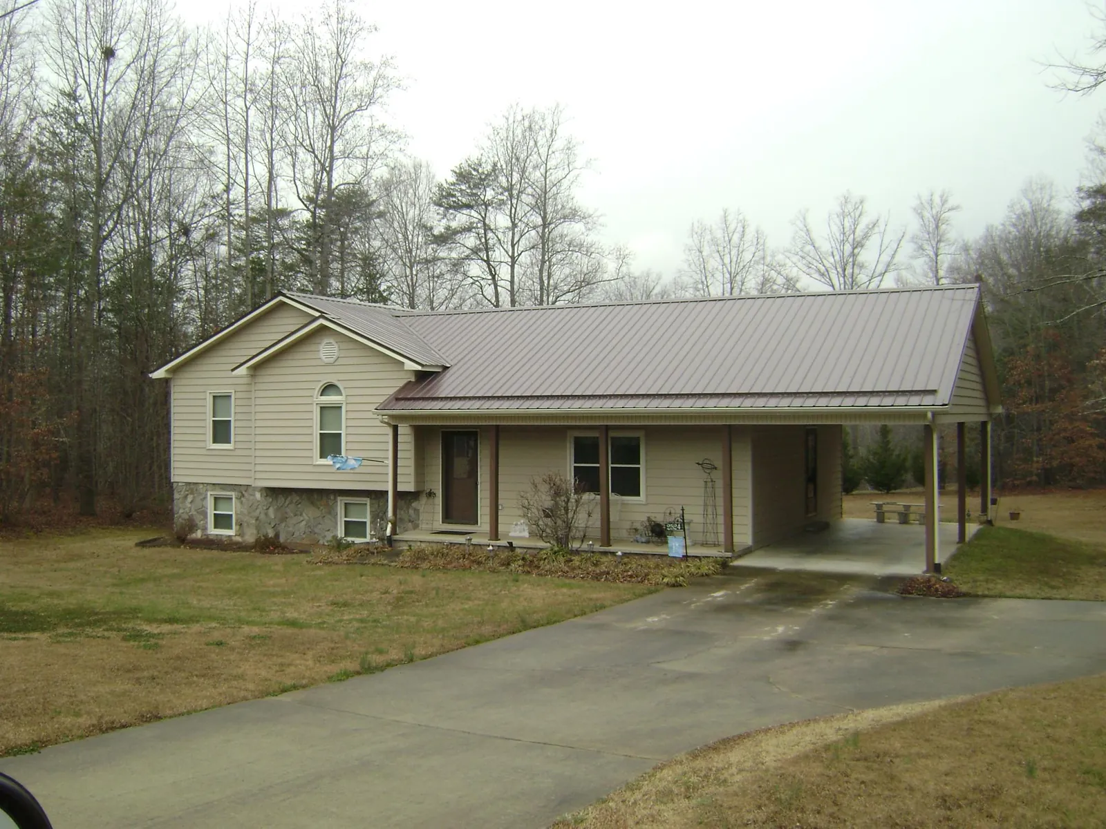 Brown metal roof on a tan split level home with an attached carport in Turner
