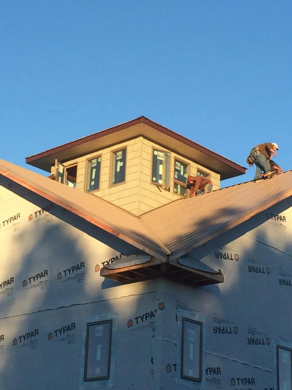 Roofers working around a rooftop cupola on a new metal roof at sunset — Roof Waterproofing in Turner by Roofing Brothers
